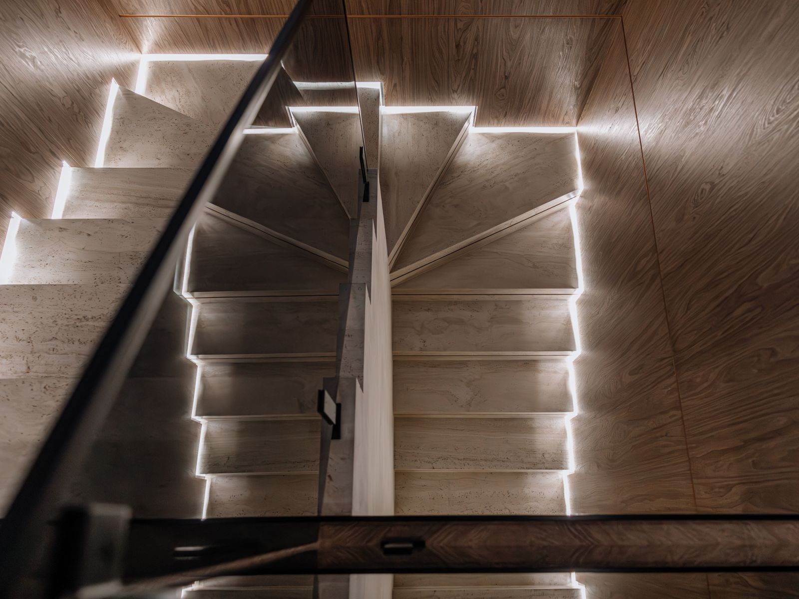 Backlighting frames the timber-finish stairs dramatically