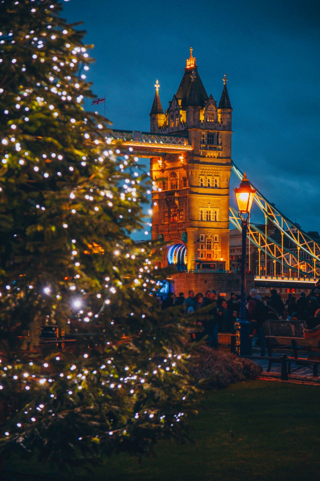 View of a colourful festive Christmas Tree with holiday lights and Tower Bridge in the background at night, London, England