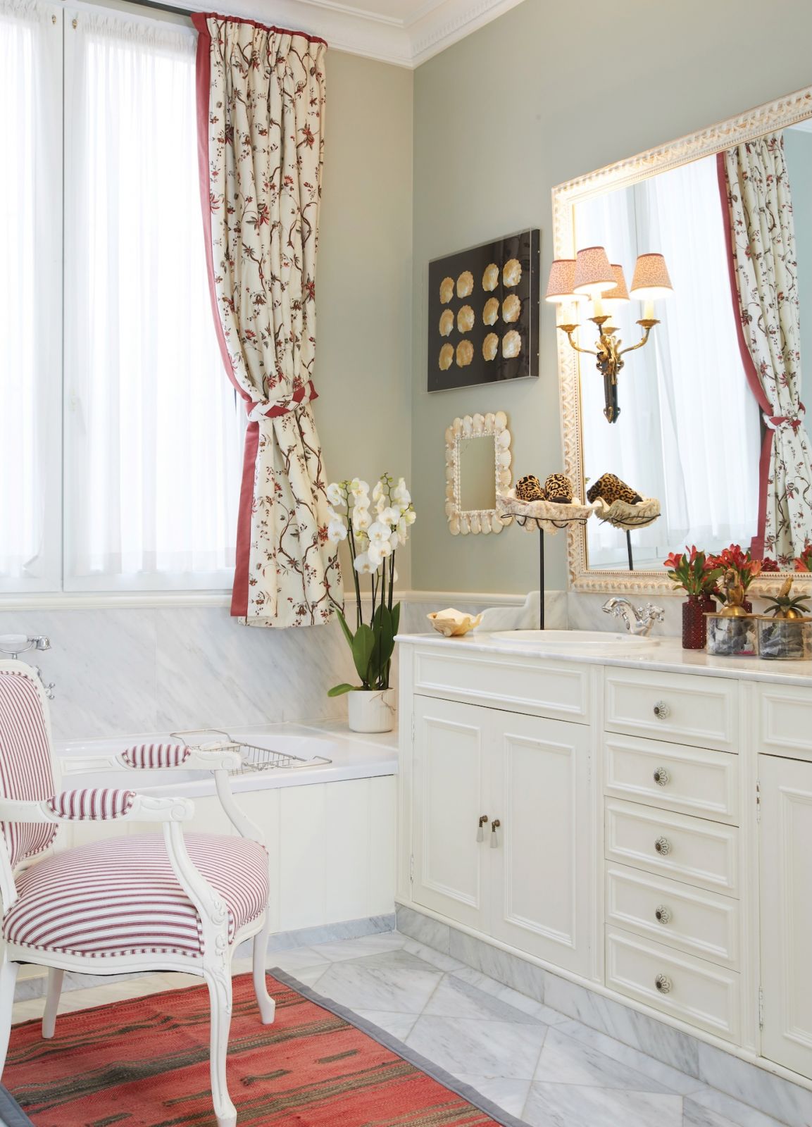 The main bathroom continues the theme of the master bedroom by using the curtains in the same fabric by Braquenié Pierre Frey fabric along with French antique chair in Colefax stripe