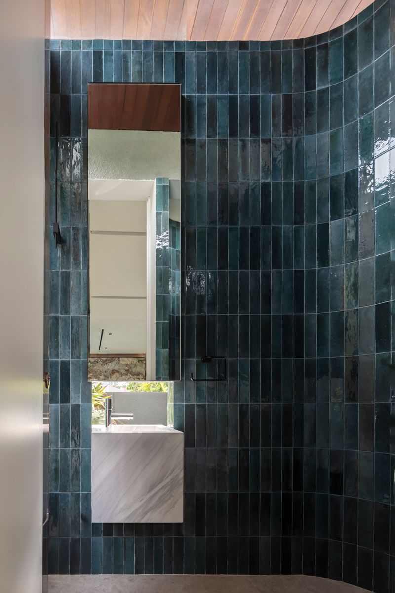 The curvy powder room enjoys ample natural light and natural air from the gap below the ceiling