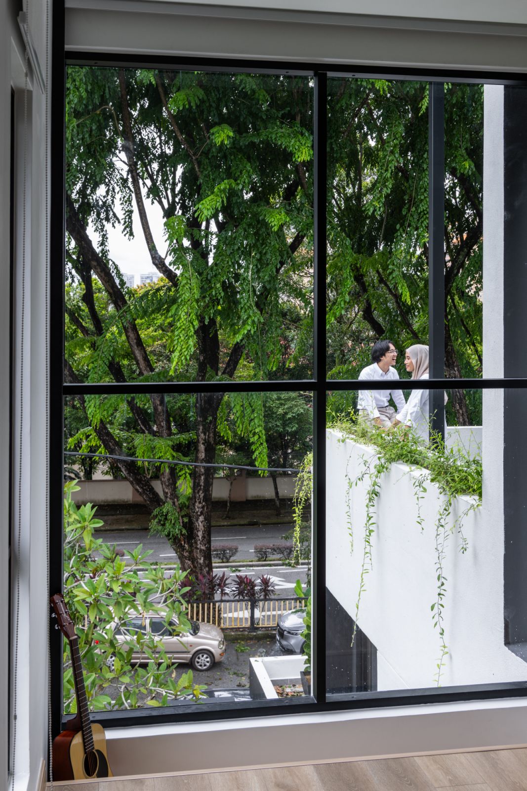 A closer view of the home's contemporary architecture showcases the thoughtful integration of green elements, with carefully placed planters creating a living façade that softens the bold black and white geometric design