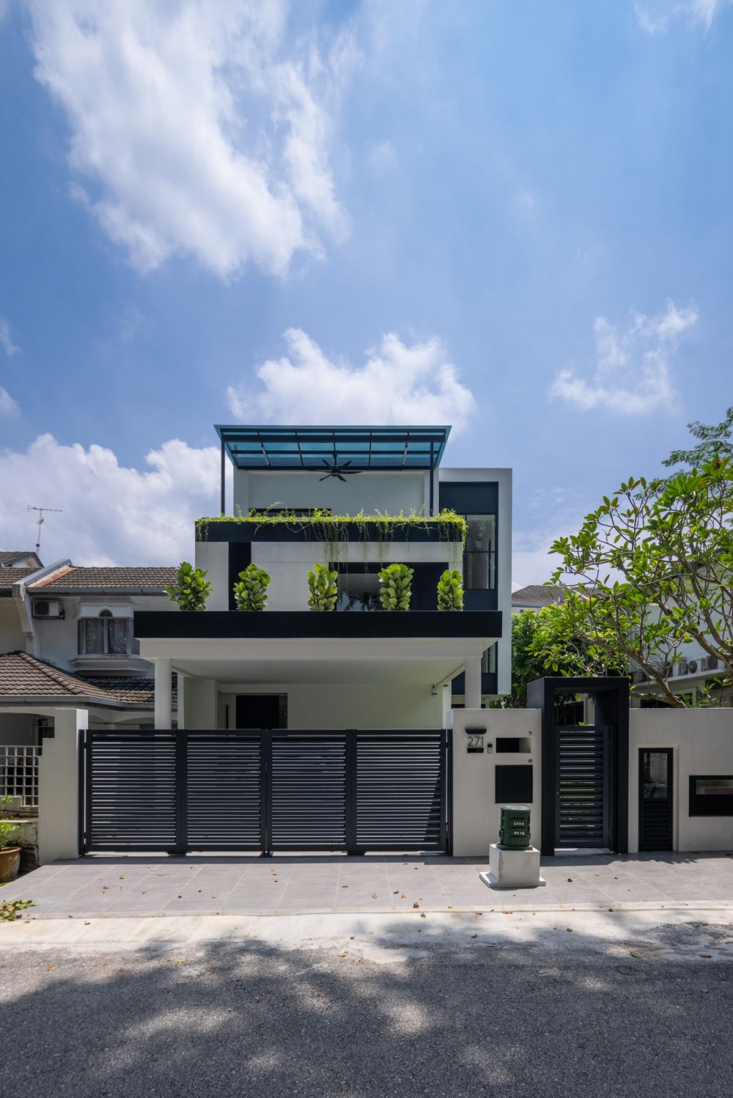 The renovated TTDI home features a striking modern façade with a distinctive blue-tinted glass canopy and vertical gardens