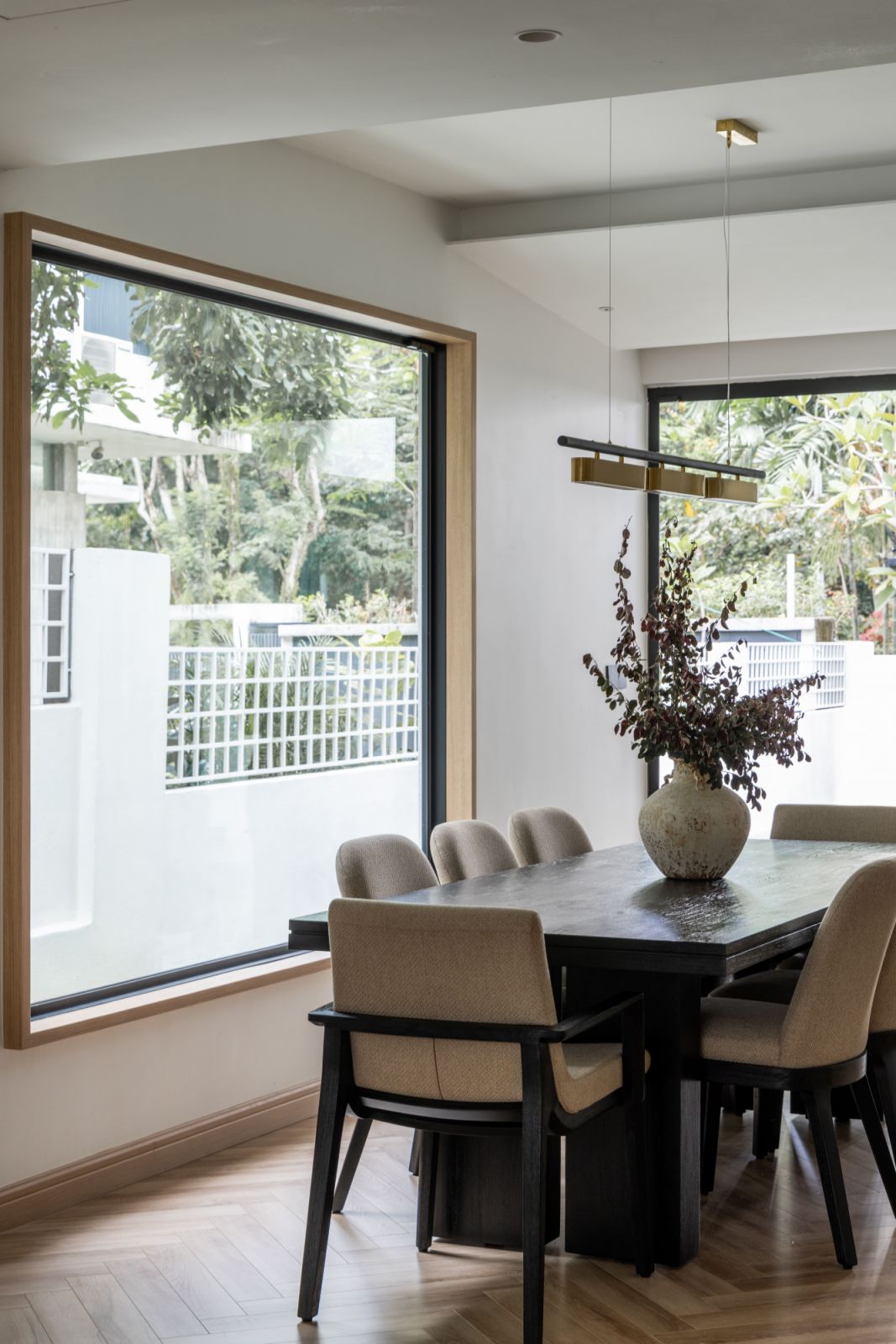 The dining area exemplifies Framework Studio's emphasis on natural light, featuring large windows that frame the garden views