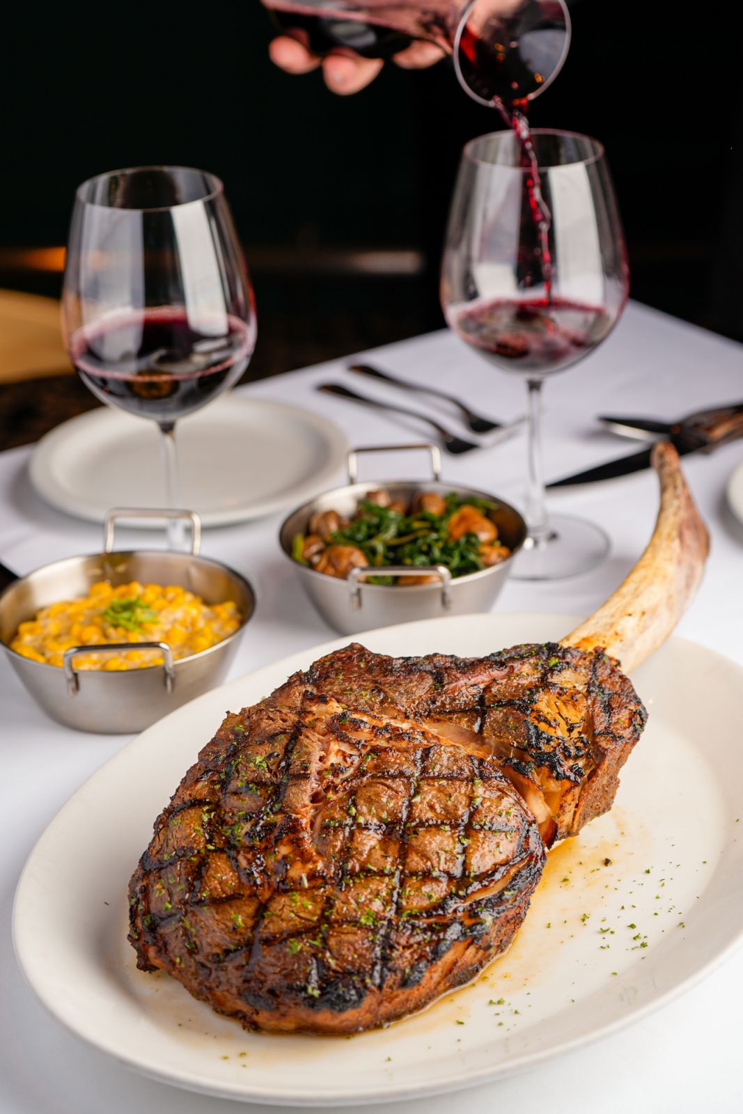 Morton's prime bone-in ribeye brushed with garlic butter and served with the classic creamed corn and sautéed spinach and button mushrooms (Photo: Morton's The Steakhouse)