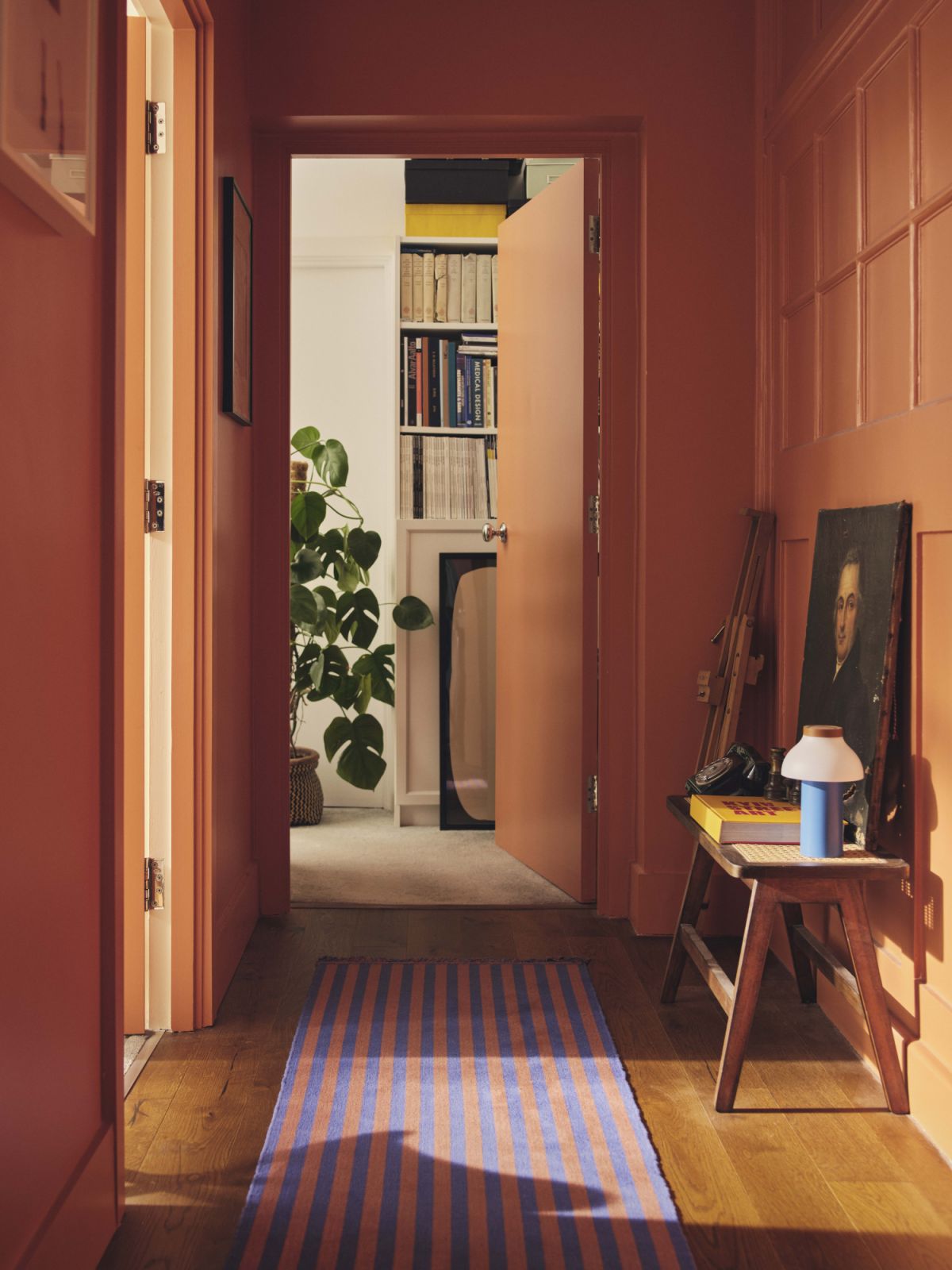 A short corridor painted in a soft sunset orange hue, adorned with an oil painting by Andre Jean Antoine Despois from 1828 (Photo: Nick Rochowski)