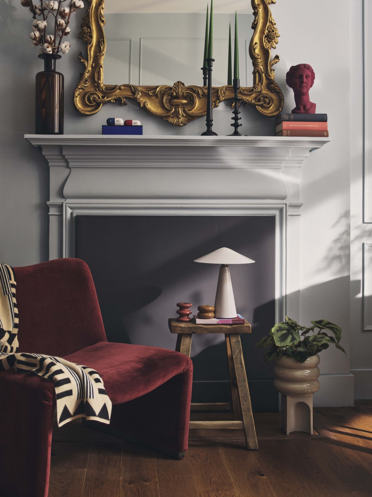An 18th century Italian rococo mirror from Christie’s sits above the mantlepiece, where a Giancarlo Piretti lounge chair from 1stDibs, Roos Vanderkerckhove throw, a burgundy head bust from Artemest and various accessories play a contrast to the muted blue walls in the drawing room (Photo: Nick Rochowski)