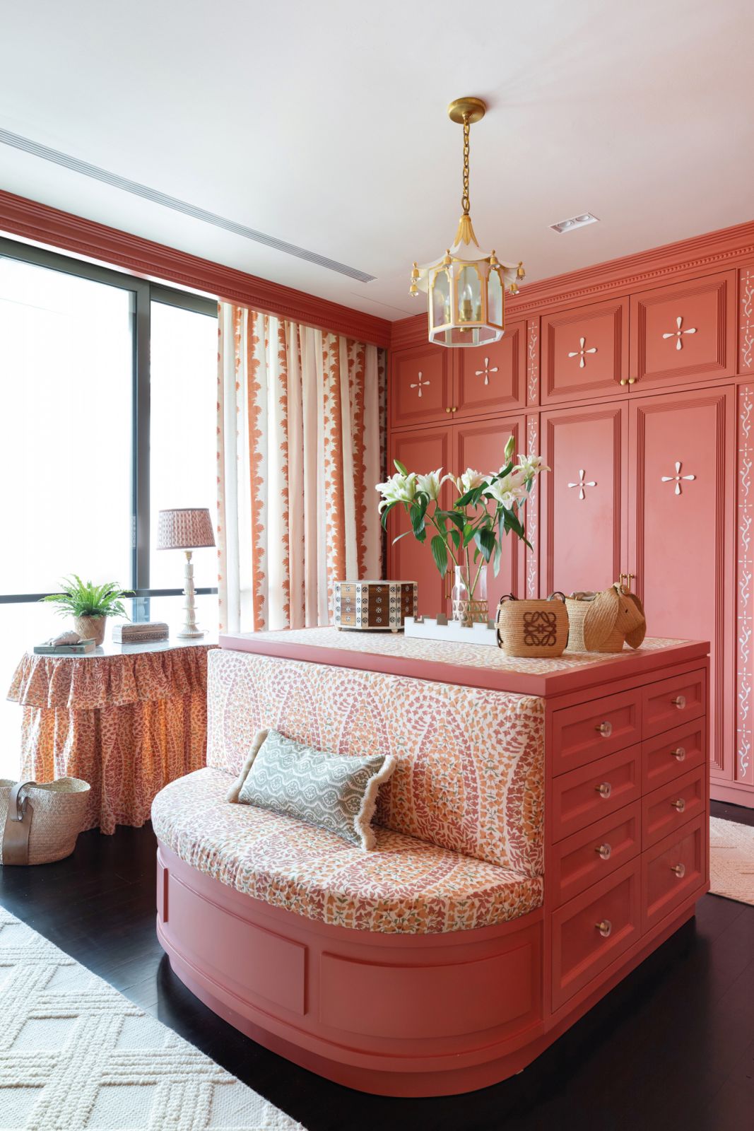 The walk-in wardrobe continues the coral colour scheme of the master suite for a unified look