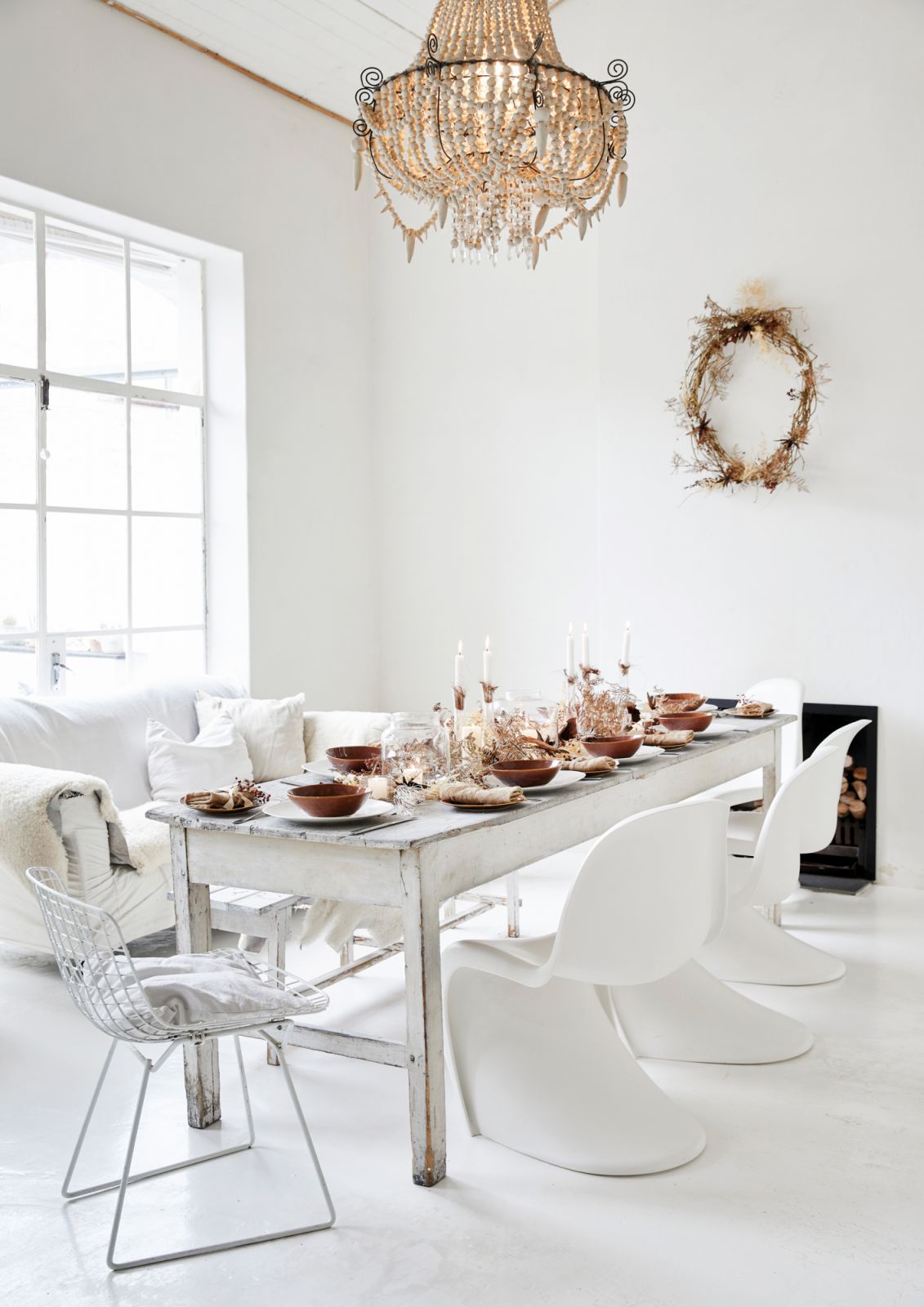 This space pairs a vintage sofa, mid-century wire chair, rustic bench and Verner Panton originals, as well as a beaded chandelier from Mud Studio to complete the cosy, celebratory mood