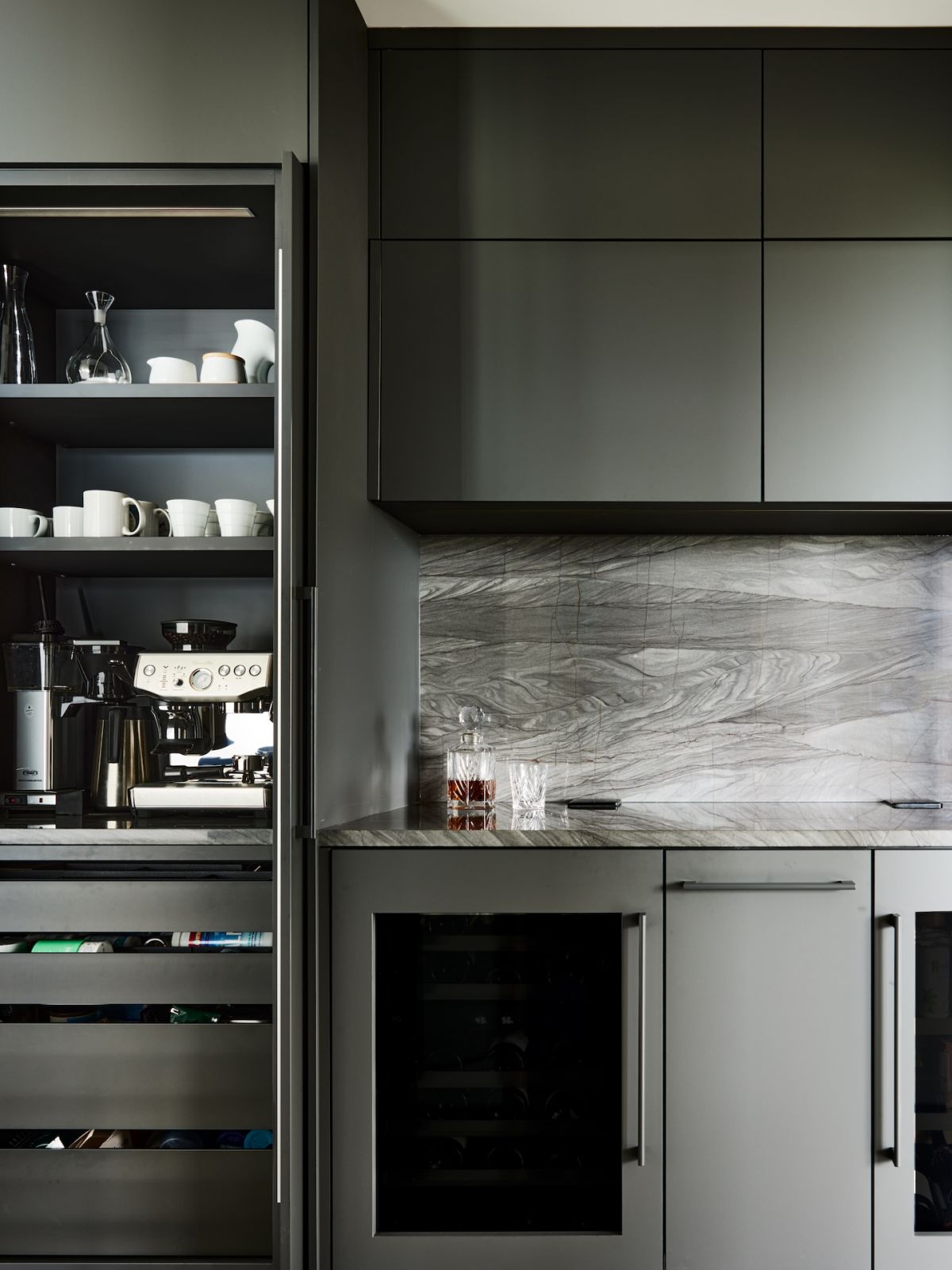 Details of the kitchen with dark cabinetry and a stone backdrop
