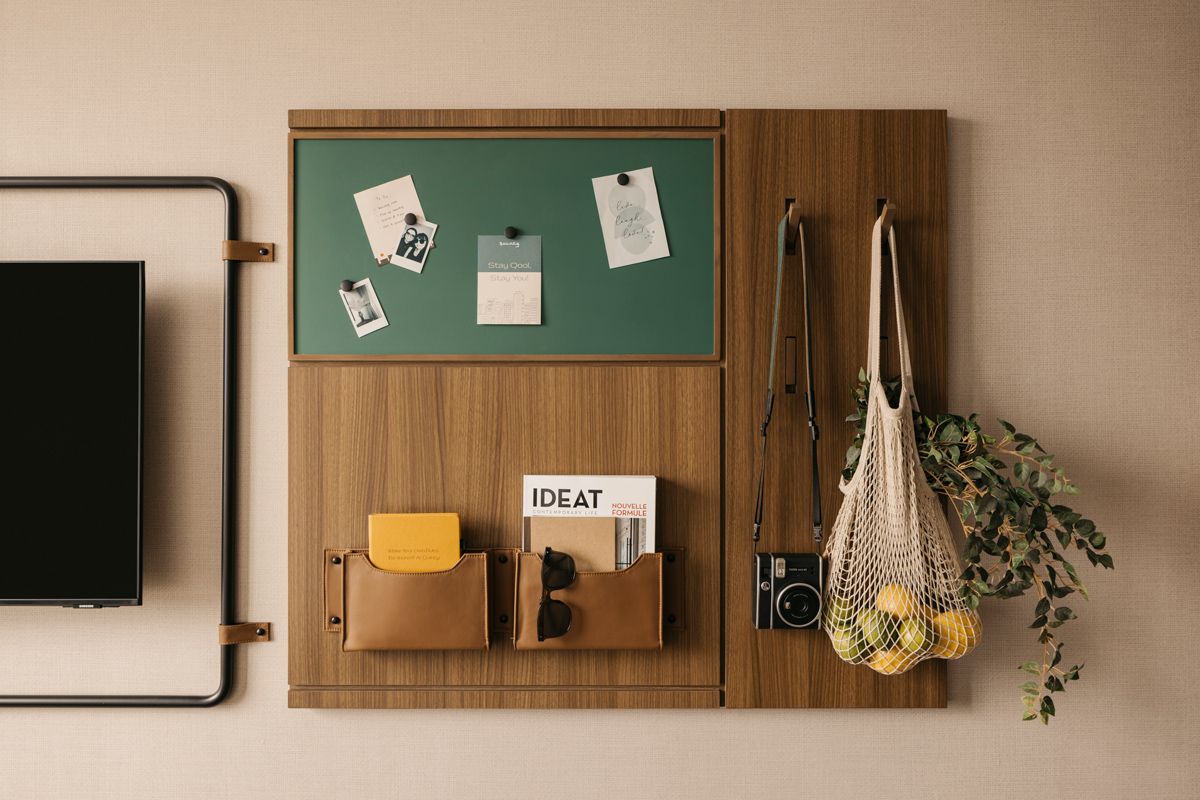 The inventive wall-mounted bulletin board doubles as a coat and bag hanger