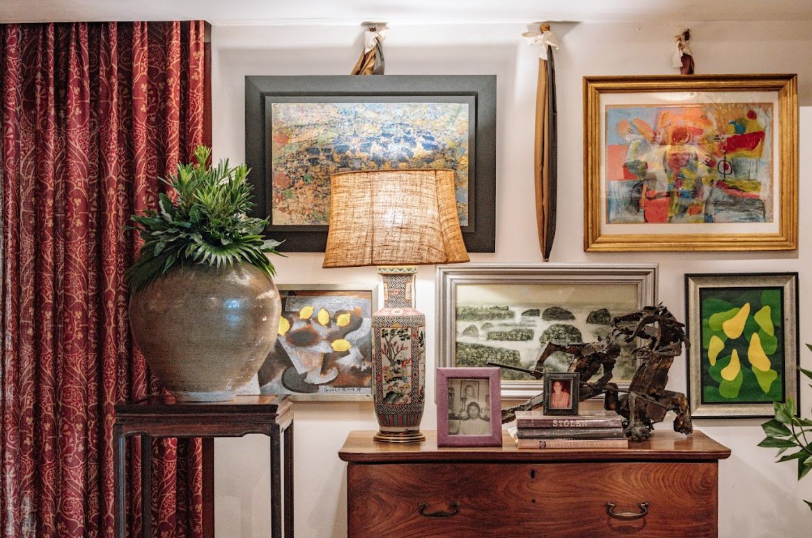 A 19thcentury church hacha made to a lampshade, a marbletop table, and a kamagong and Narra Ilocano cabinet; Antique French sconces; Paintings hung in the salon style-Vitalis, Alcuaz, Sanso, and HR Ocampo. A Qing lampshade and Solomon Saprid’s Don Quijote on a rare 19th century Narra Serpentine chest of drawers