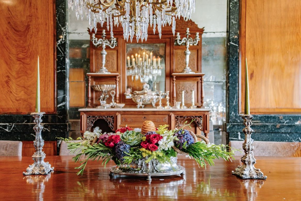 The dining room with narra panelling enveloped with green marble. The Paterno marble-top buffet table from the 19th century against an antiqued-mirror as background and an Osmundo custom table with B&B Italia chairs. The silver candlesticks flank an old silver centro de mesa for the flowers