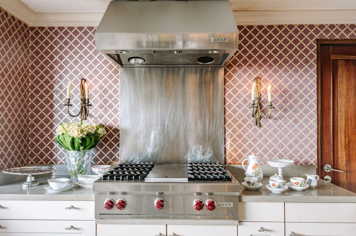 The kitchen in Stark wallpaper with Meissen porcelain; Silver accoutrements onn top of a 19th century Baliuag commode and a French crystal chandelier with faux candles seen from the antique mirror