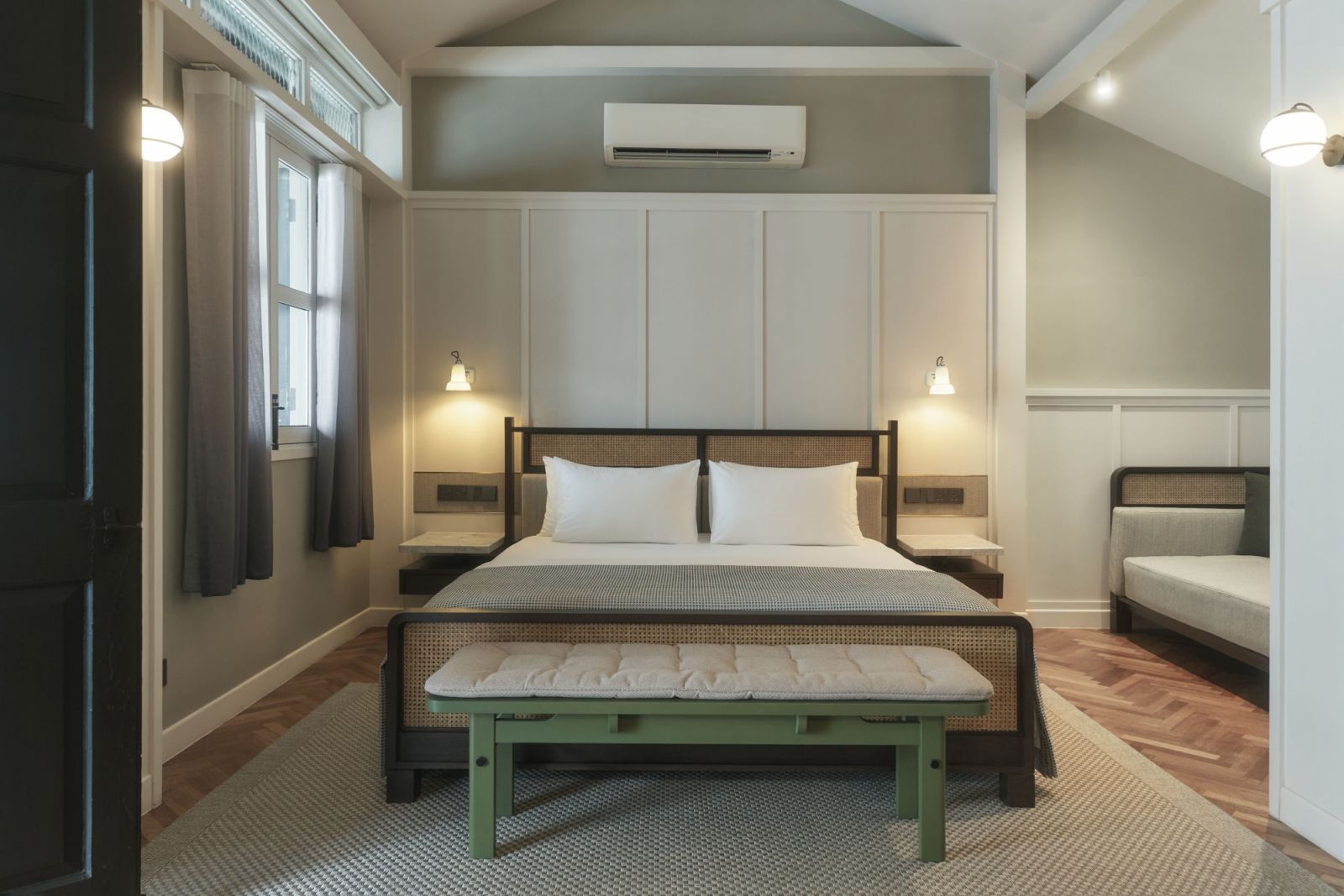 Each renovated guest room showcases By Hogen’s locally crafted furniture, including mint green benches, set against a backdrop of herringbone floors and paneled walls