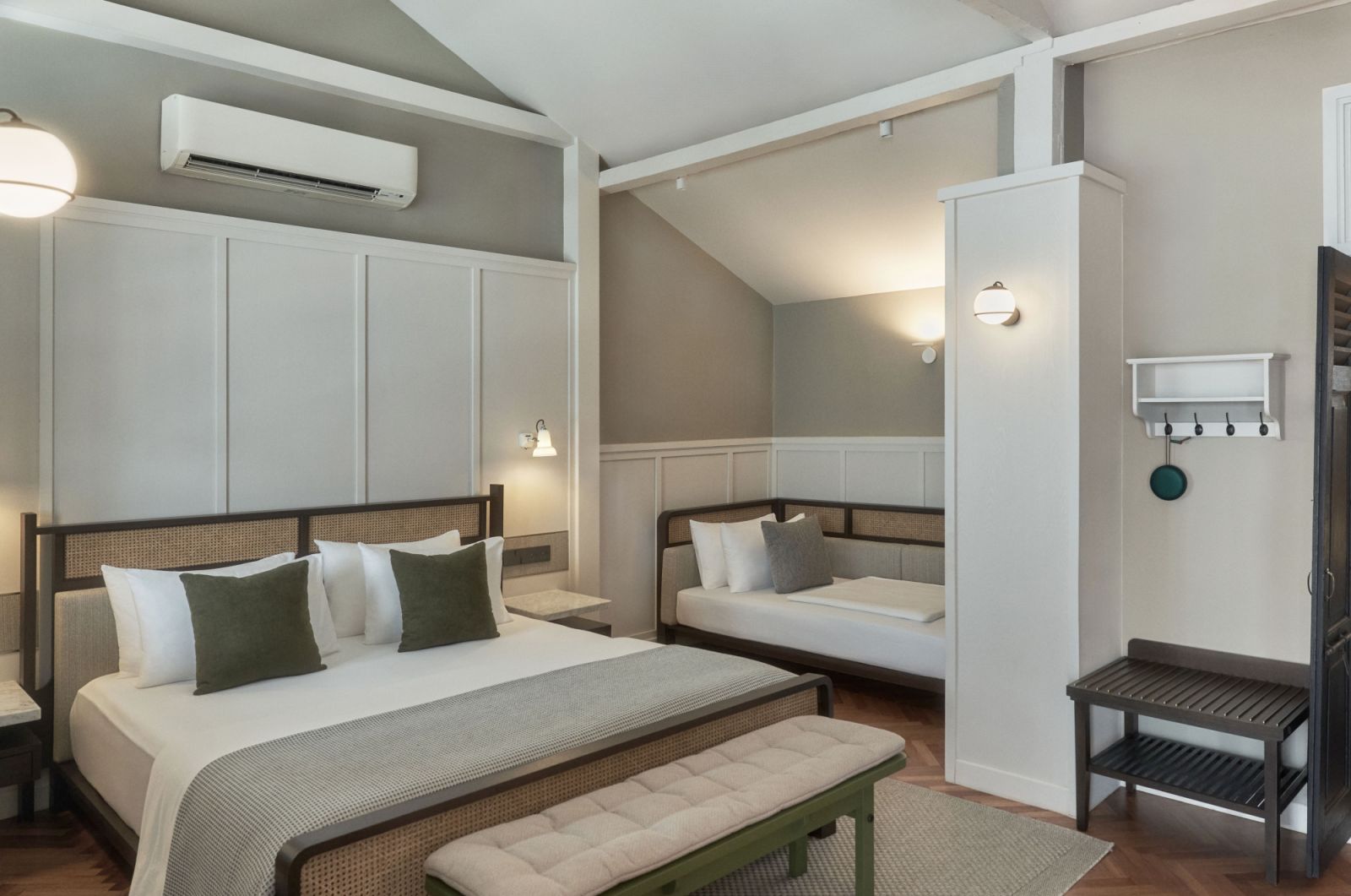 The spacious Mews rooms blend comfort with heritage, featuring custom-designed daybeds, rattan furnishings, and thoughtful details like vintage-inspired wall sconces and coat hook