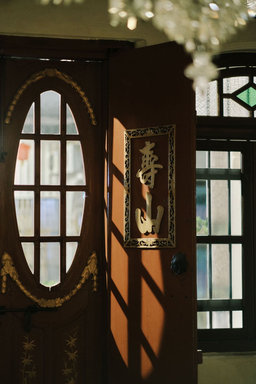Traditional Chinese architectural elements, including an oval-shaped window frame and carved wall art, capture the cultural fusion characteristic of Penang's historic shophouses