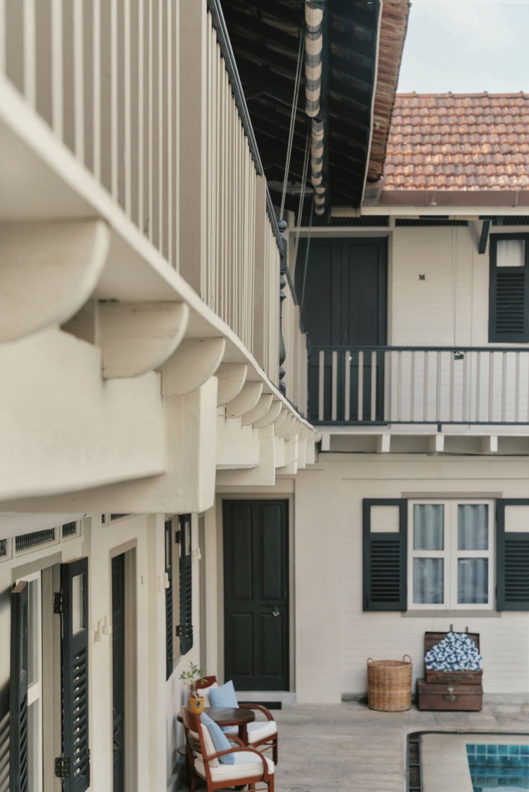 The mews section showcases classic colonial architectural details with its distinctive white corbels, green shutters, and terracotta roof tiles