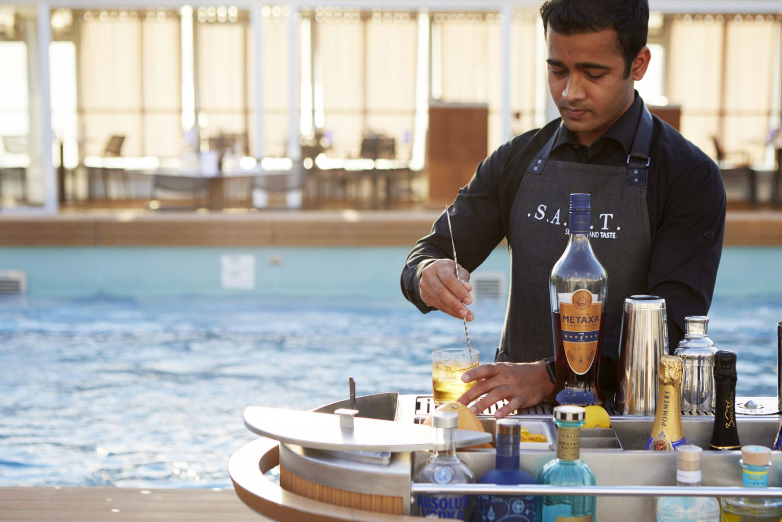 A bartender is making customised cocktails for the guests by the pool.