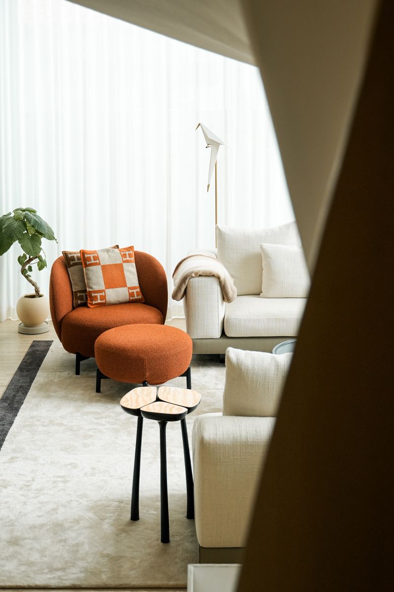 HG Group's spiral staircase's structural frame lends an edgy foreground to the living room's elegant furniture