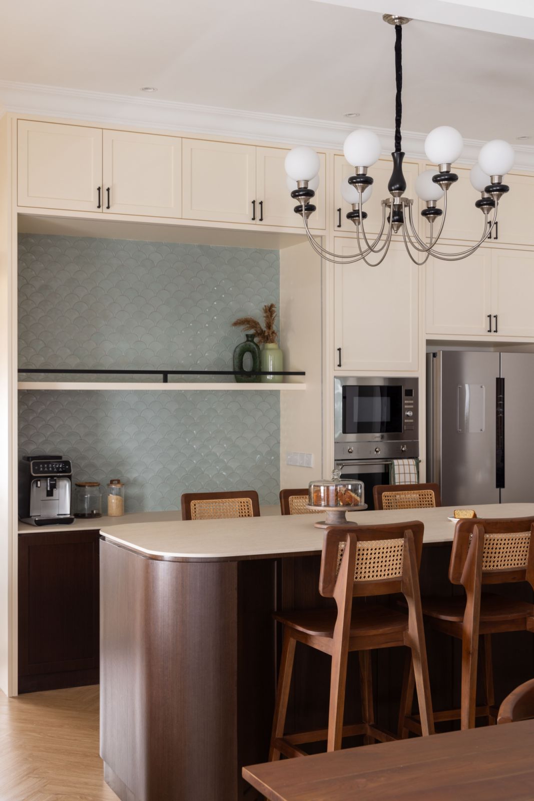 Fish scale tiles in deep green shimmer across the kitchen backsplash offering a textural counterpoint to the sleek Dekton countertops