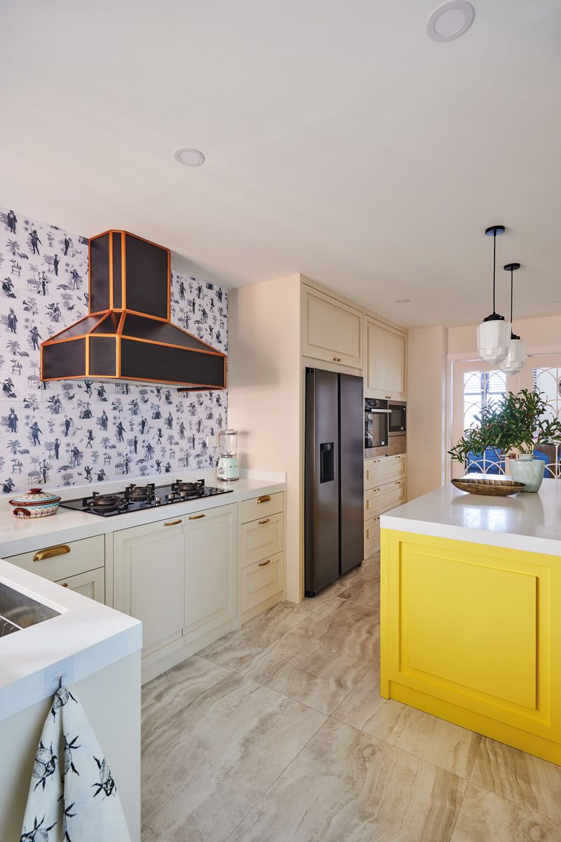 A gold-trimmed extractor hood and wallpaper lend a graphic edge to the kitchen