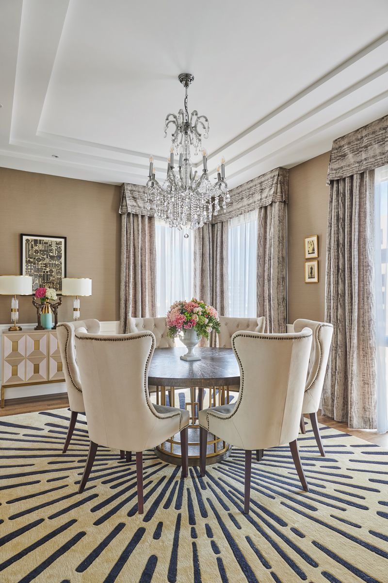 The elegant dining room features high-back chairs and a charming custom rug