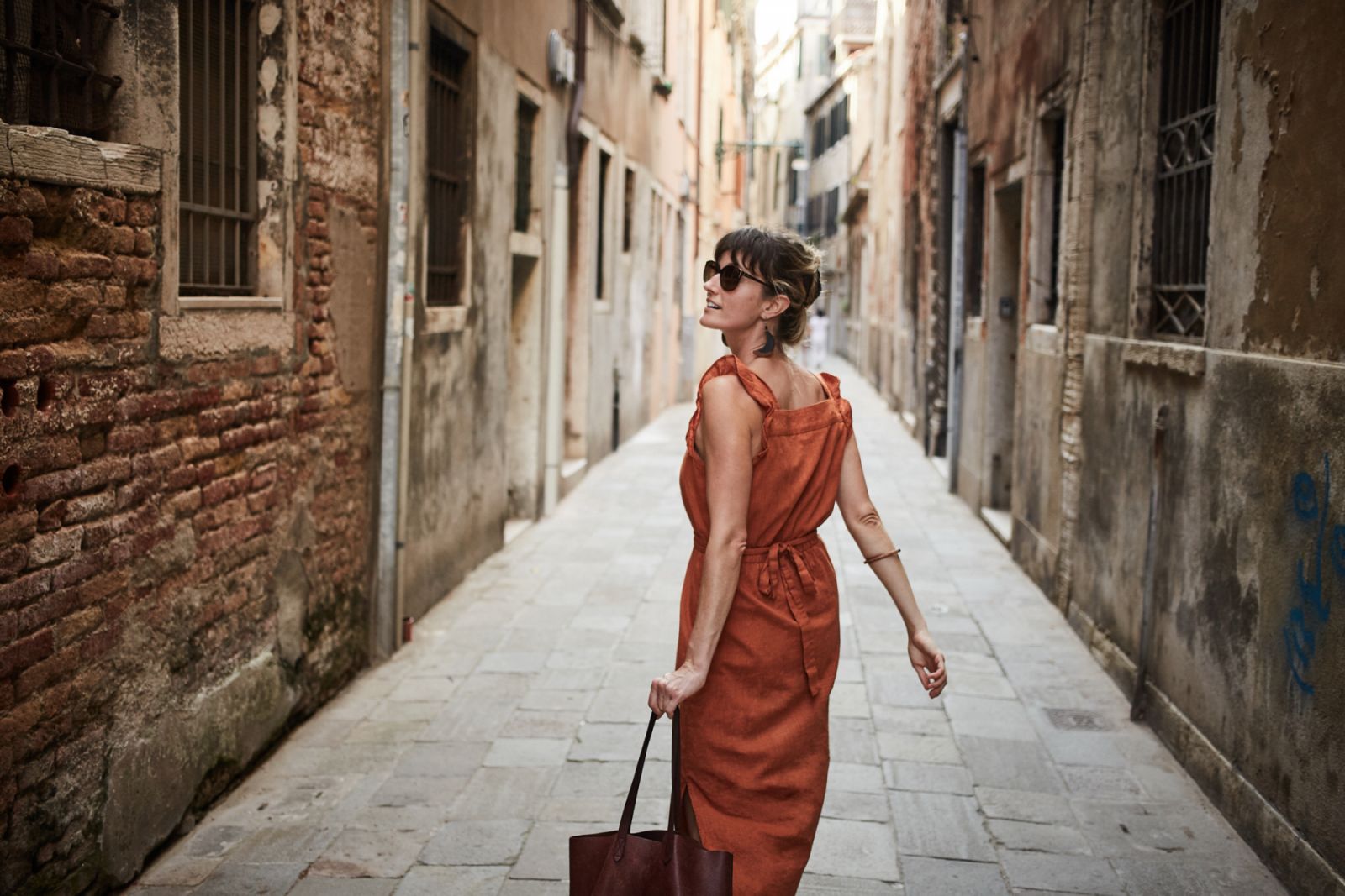 A young woman walks down an old street in Italy