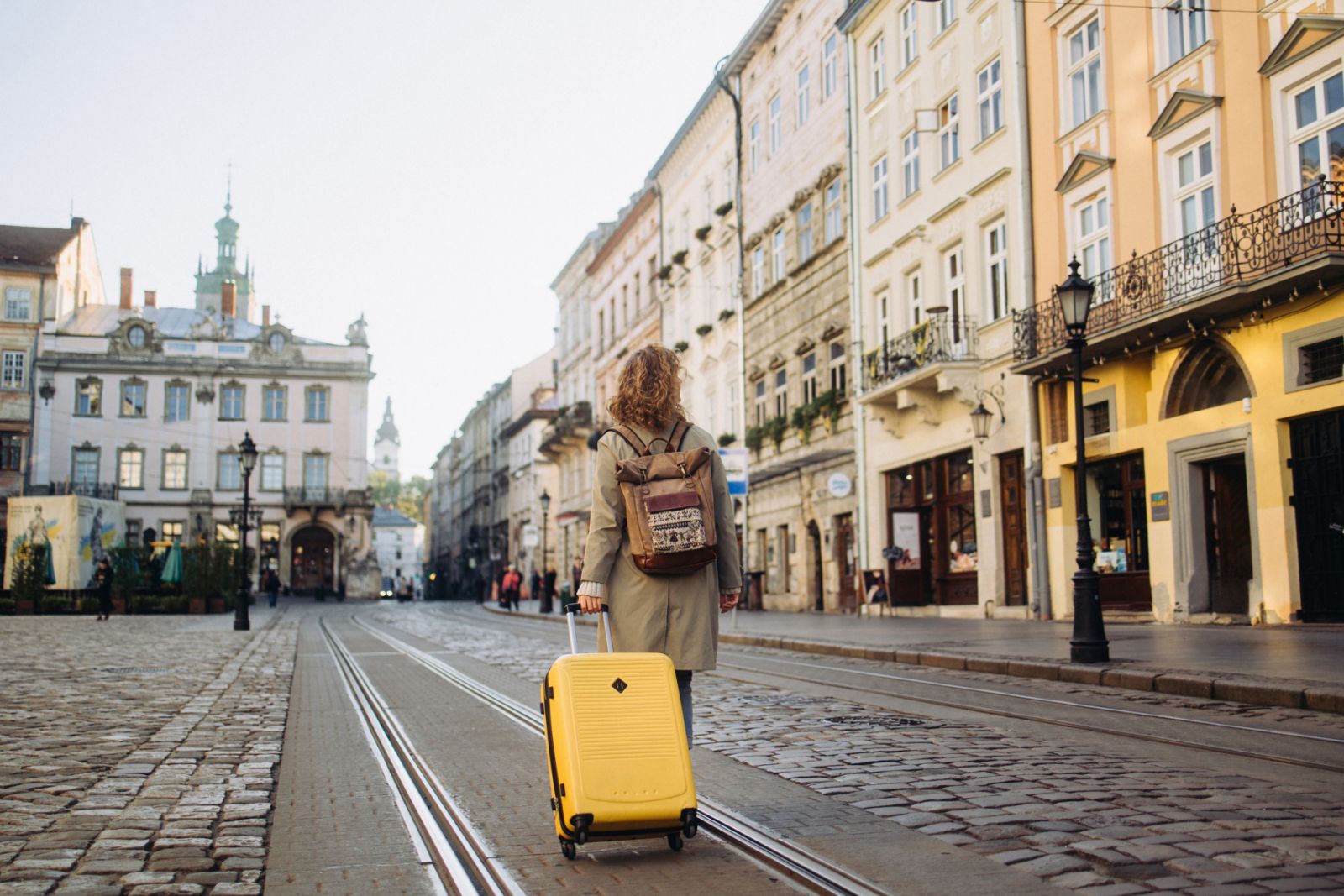 A beautiful and cheerful woman is captured as she walks along a charming, ancient European street during the autumn season