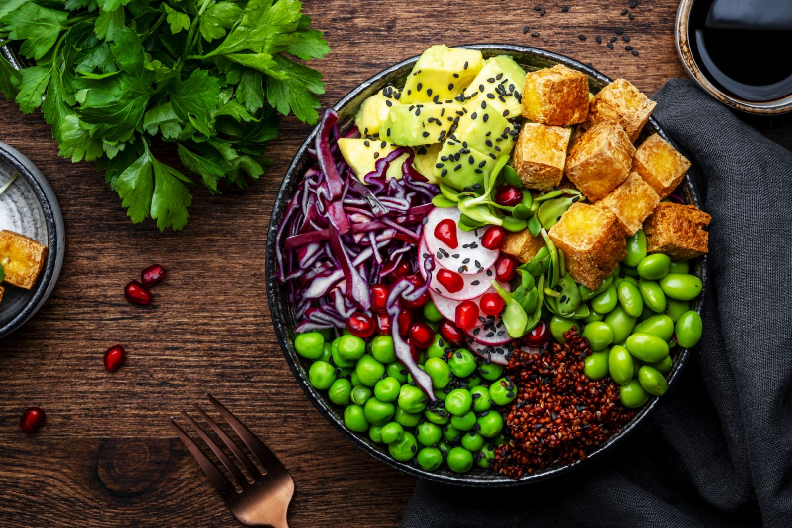 Vegan Buddha Bowl for balanced diet with tofu, quinoa, vegetables and legumes. Wooden table background, top view