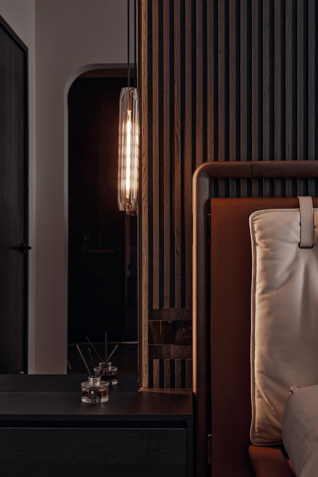 A corner detail of the bedroom, featuring a built-in side table and a pendant light