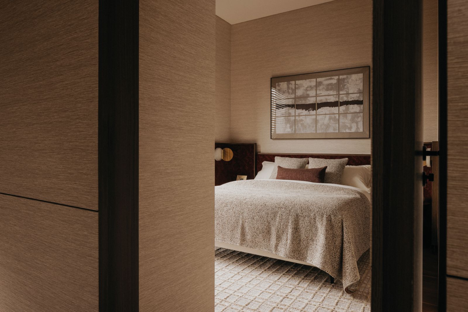 The lines in the artwork echo those on the plush rug, creating a cohesive look rich in textures in this bedroom