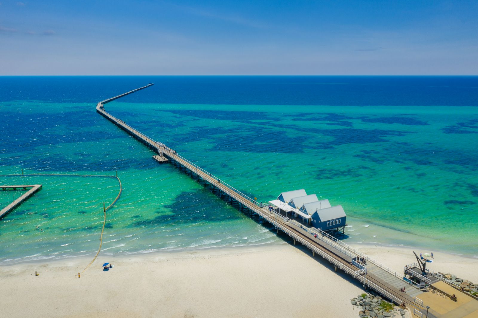 Aerial view of Busselton Jetty on a sunny day with tourists in front of souvenir shop in Busselton, Western Australia, Australia.
