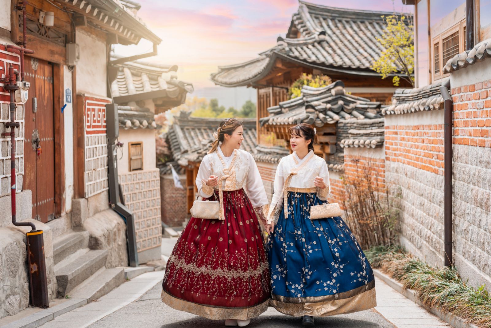 Two lovely women in hanbok stroll through the traditional-style homes of Seoul's Bukchon Hanok Village.