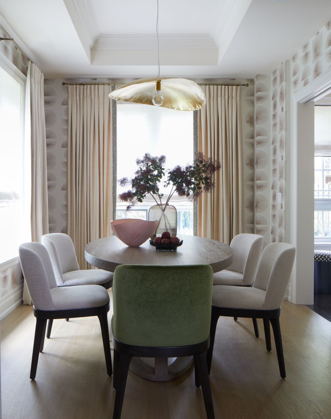 The dining room, featuring wallpaper by Philip Jeffries, a table by Robert James and green mohair dining room chairs by Clarence House