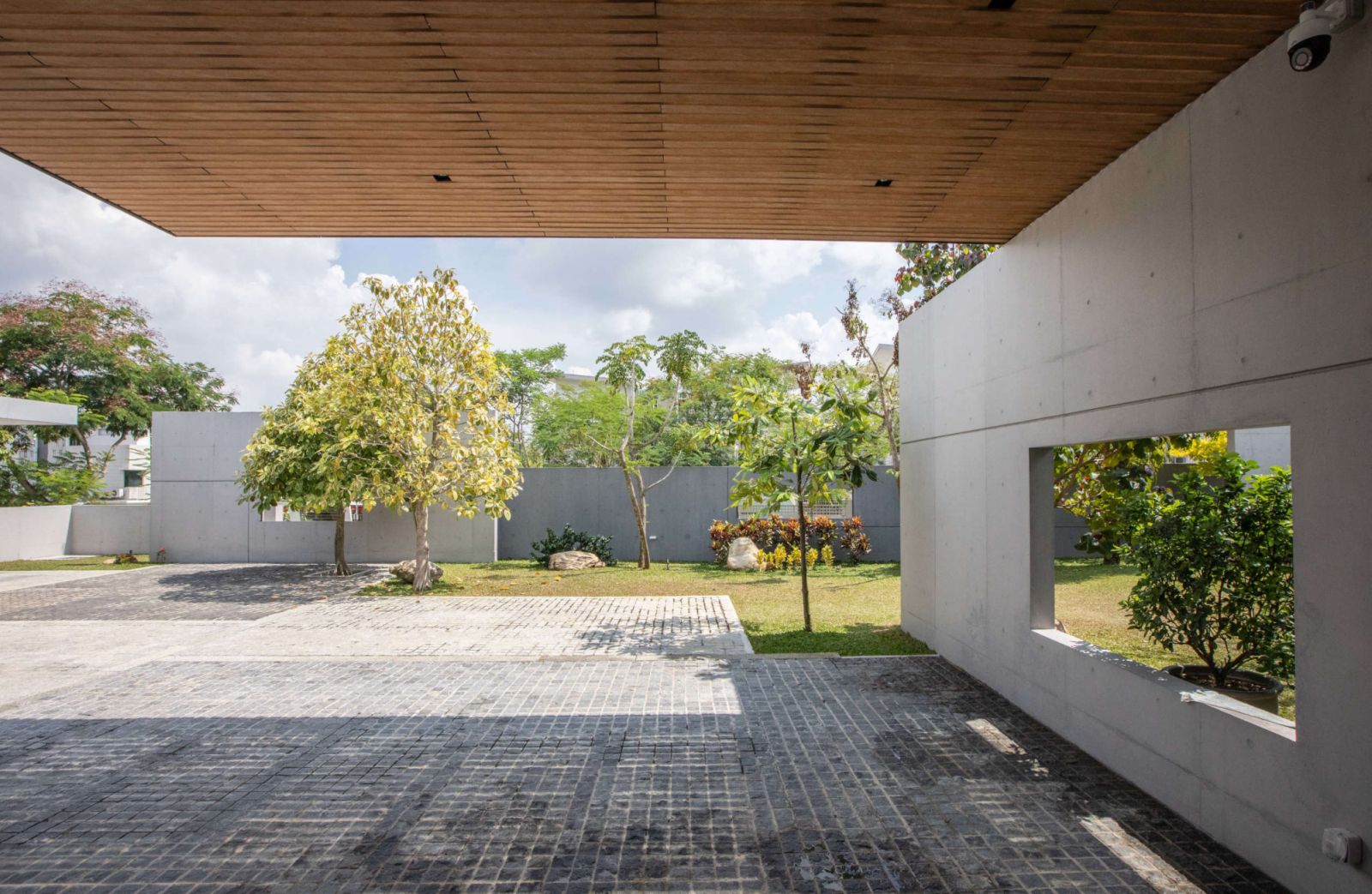 The entrance showcases its modernist principles through intersecting concrete planes and timber ceiling details