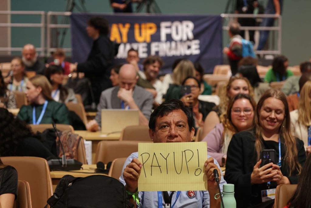 BAKU, AZERBAIJAN - NOVEMBER 21: Activists, including one holding a piece of paper with "Pay Up!" written on it, in reference to demands for climate finance for developing countries, arrive to attend the "People's Plenary" on day ten at the UNFCCC COP29 Climate Conference on November 21, 2024 in Baku, Azerbaijan. The COP29, which is running from November 11 through 22, is bringing together stakeholders, including international heads of state and other leaders, scientists, environmentalists, indigenous people