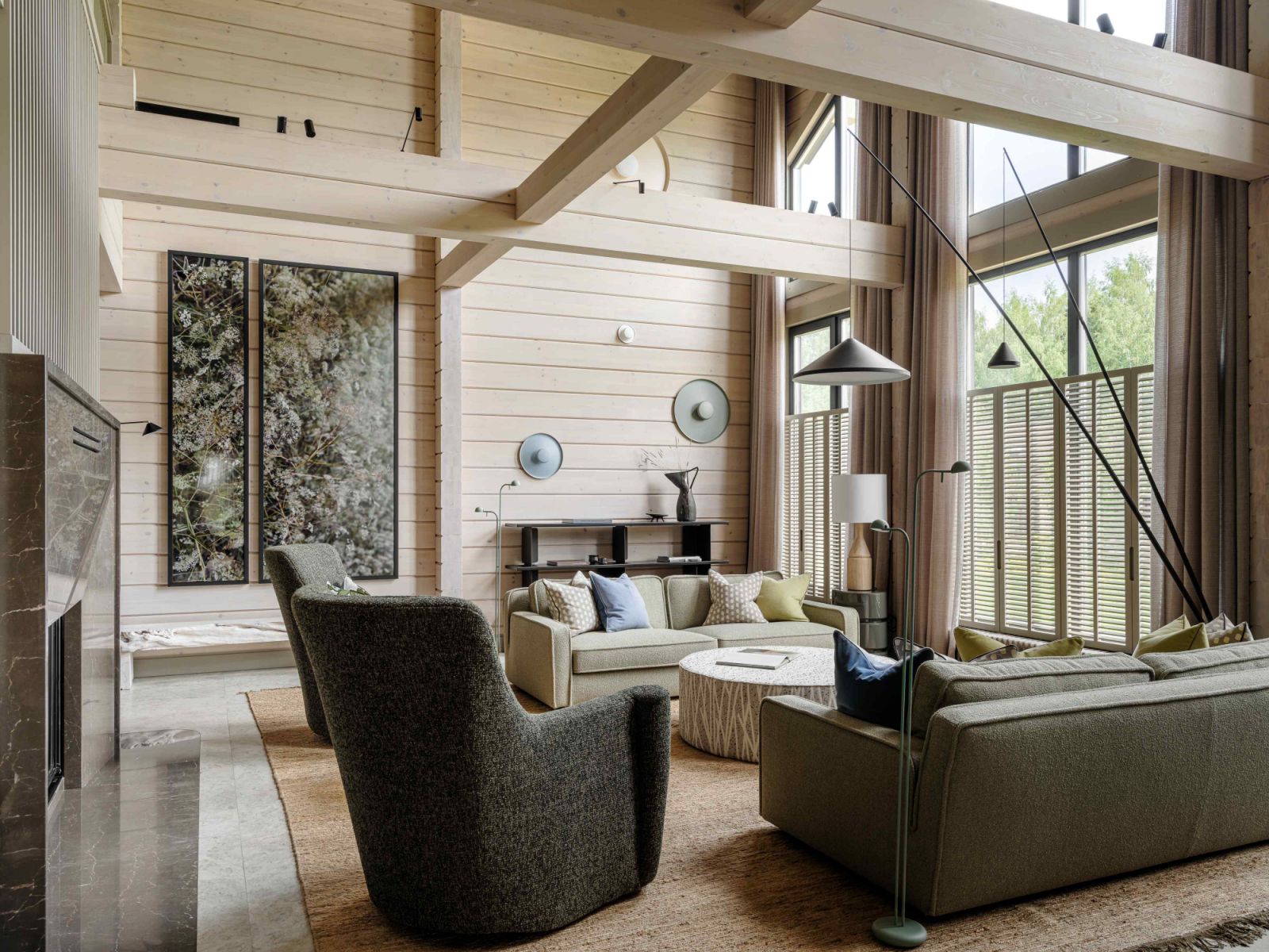 Ample light permeates the double-height living room through exposed wood beams and wooden shutters