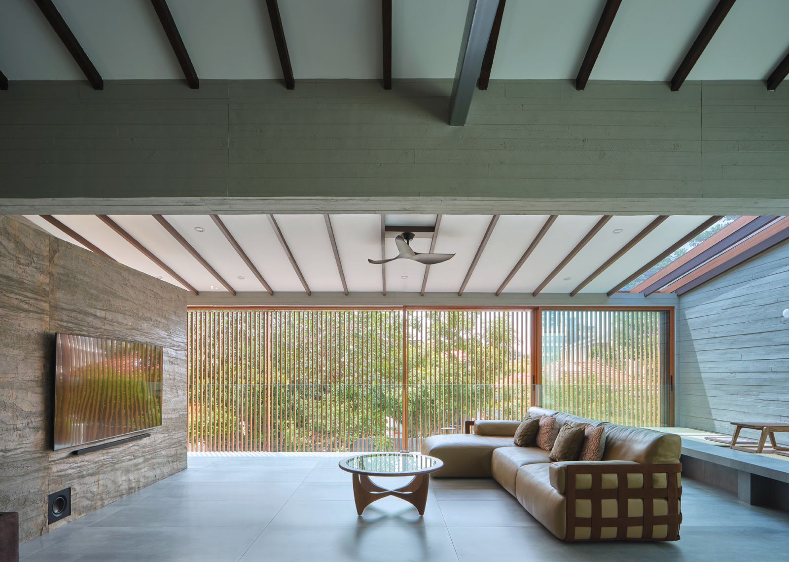 The home’s spacious living area is bathed in natural light thanks to the blending of indoor and outdoor spaces, an effect further enhanced by the use of natural materials such as stone and wood