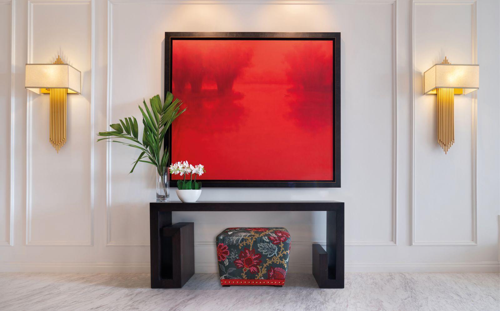 This sizeable red artwork is flanked by decorative wall lights that temper the strength of the piece