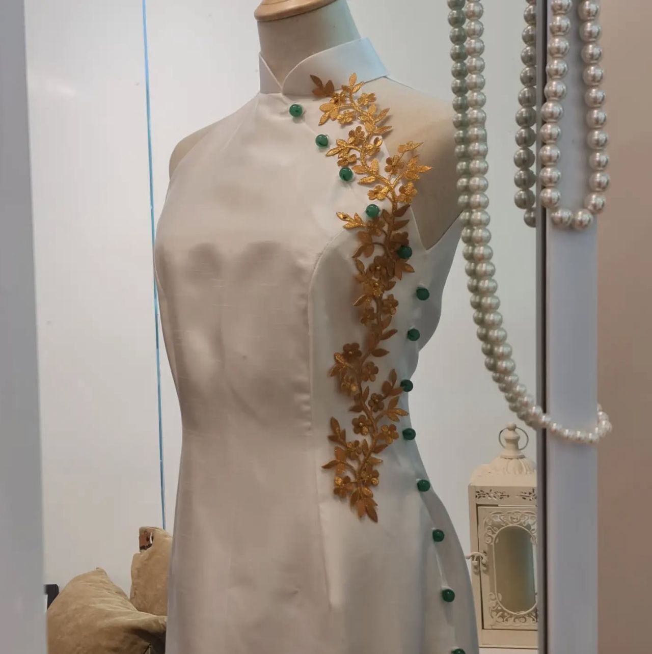White sleeveless cheongsam with full green beads, highlighted with gold appliqués (Photo: Instagram/ @outpostsg)