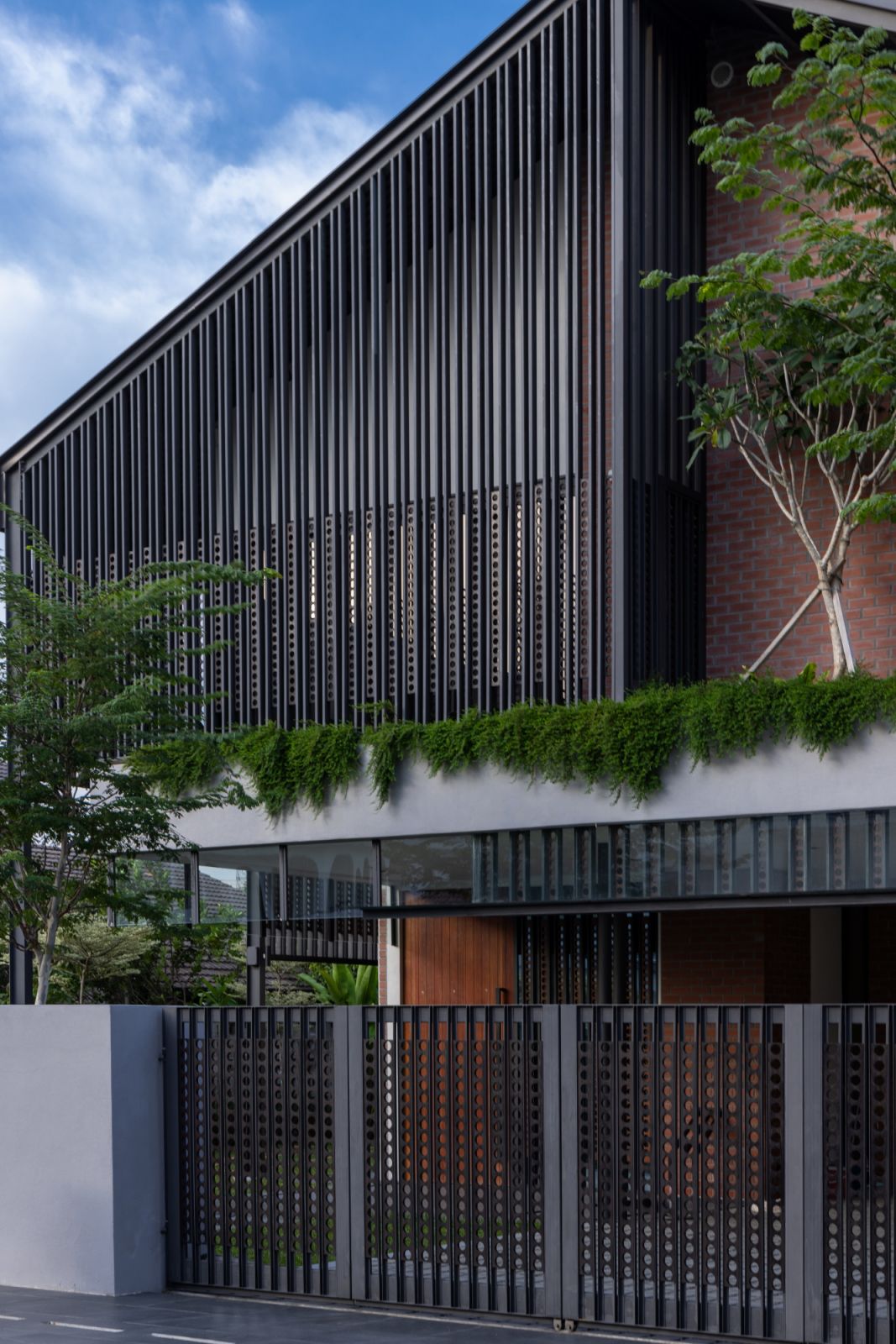 The façade works in harmony with the landscaping to create privacy while maintaining airflow