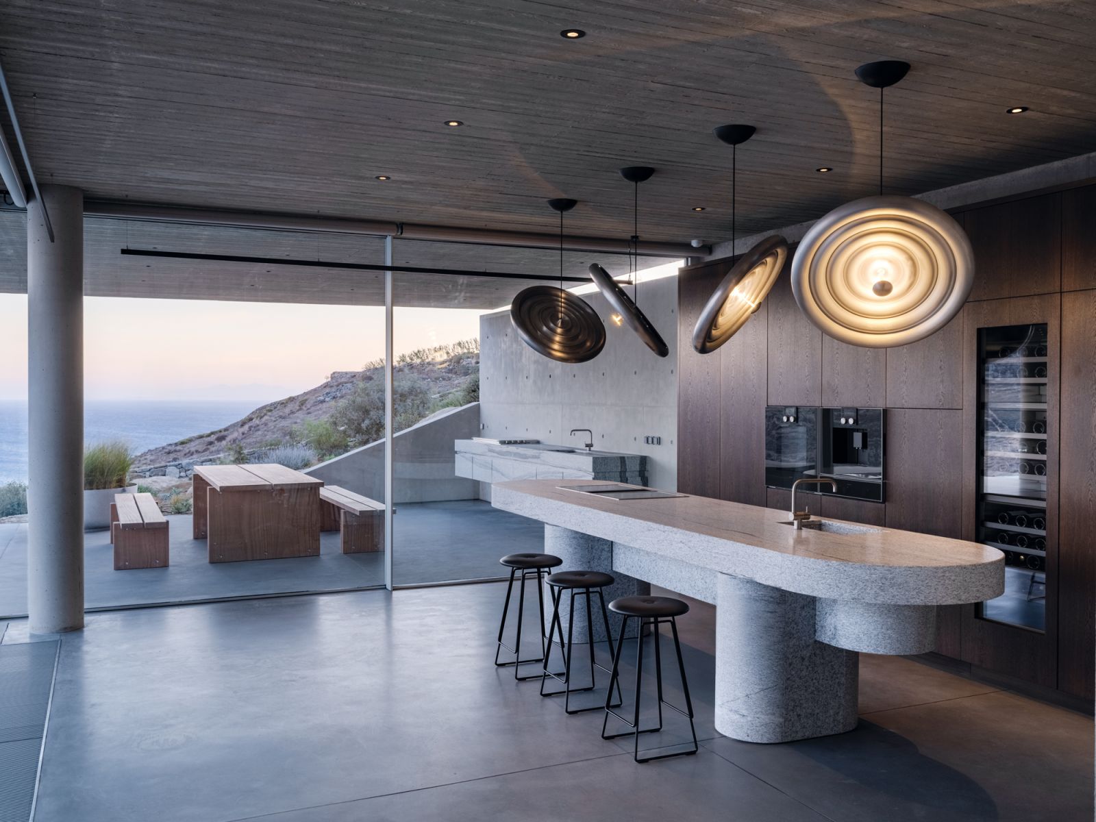 This kitchen is nestled on the terrain, with Tom Dixon statement lights adding a futuristic feel