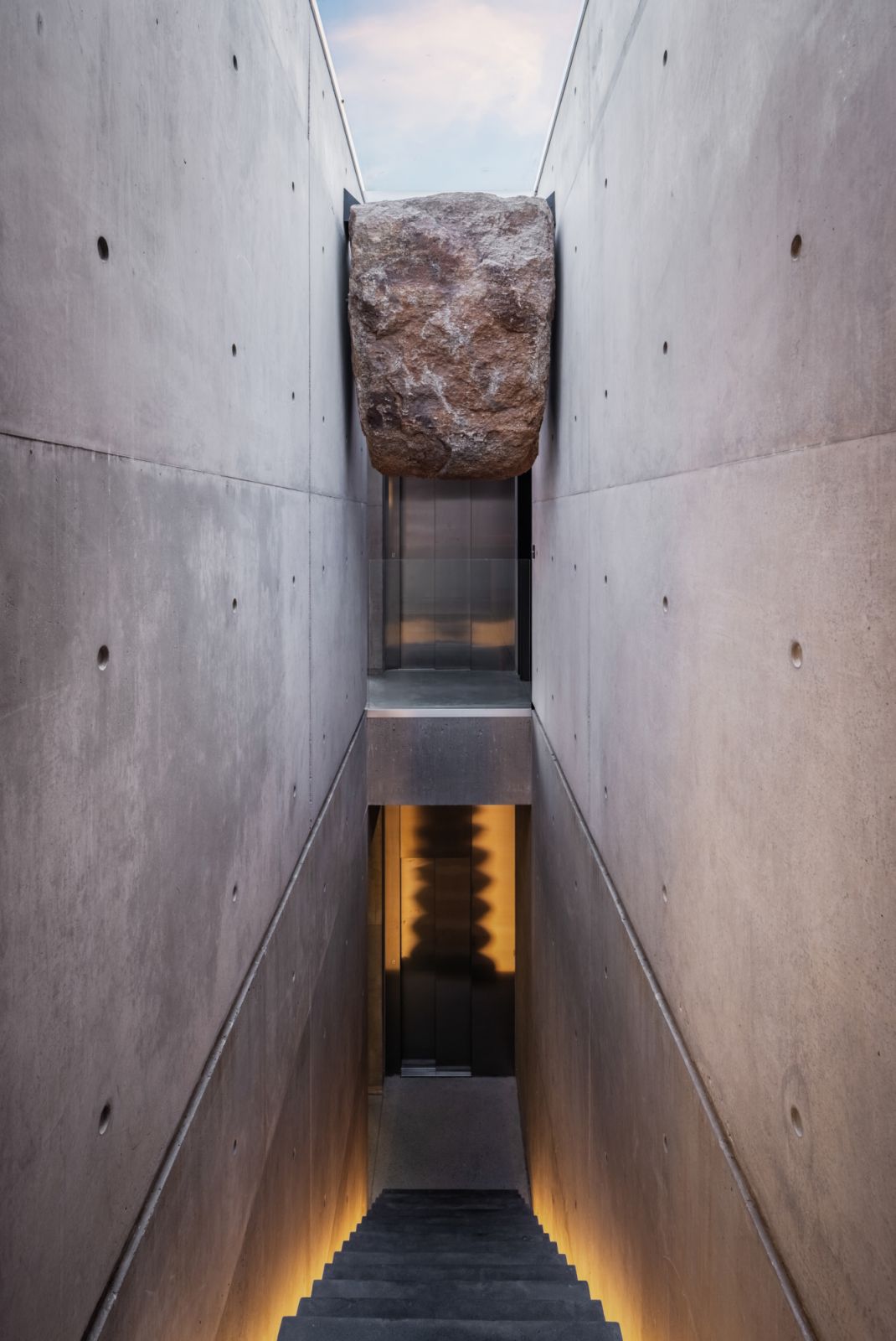 The cleverly lit stairway incorporates a boulder from the terrain as an accent