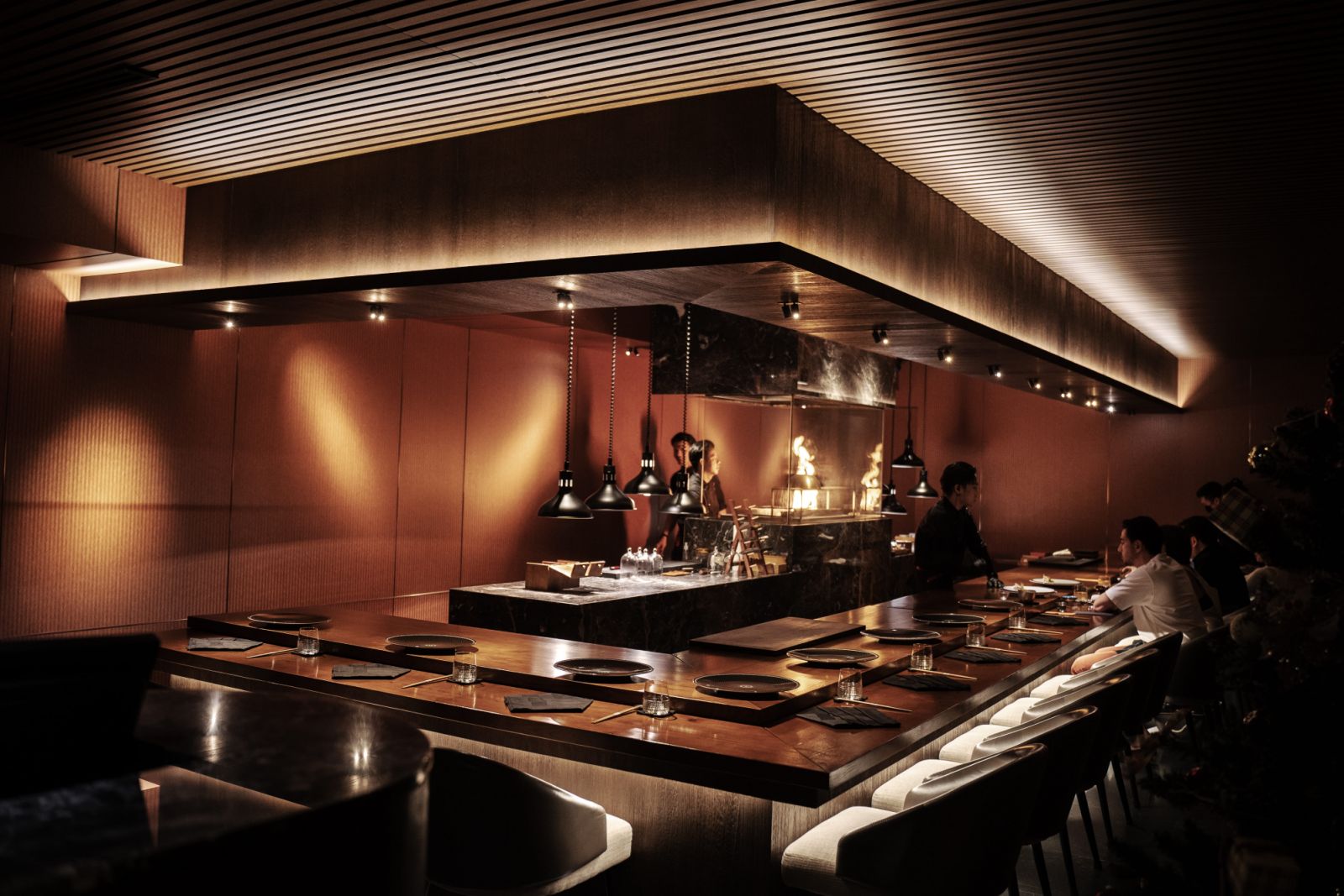 The sienna-clad dining room features a gleaming marble counter that seats just 12, where diners can watch their meals prepared on binchotan charcoal behind glass