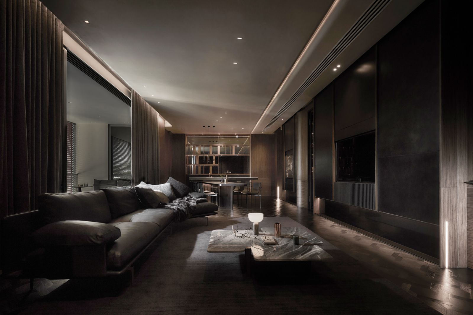 The tantalisingly moody living space in an all-dark material palette reveals itself through slivers of light