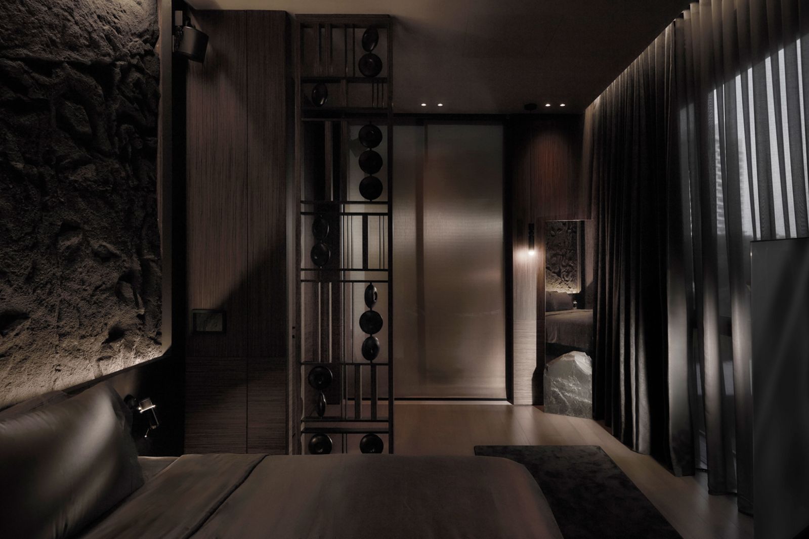 Smoke-hued curtains filter in natural light while moody downlights illuminate the various textures in this bedroom