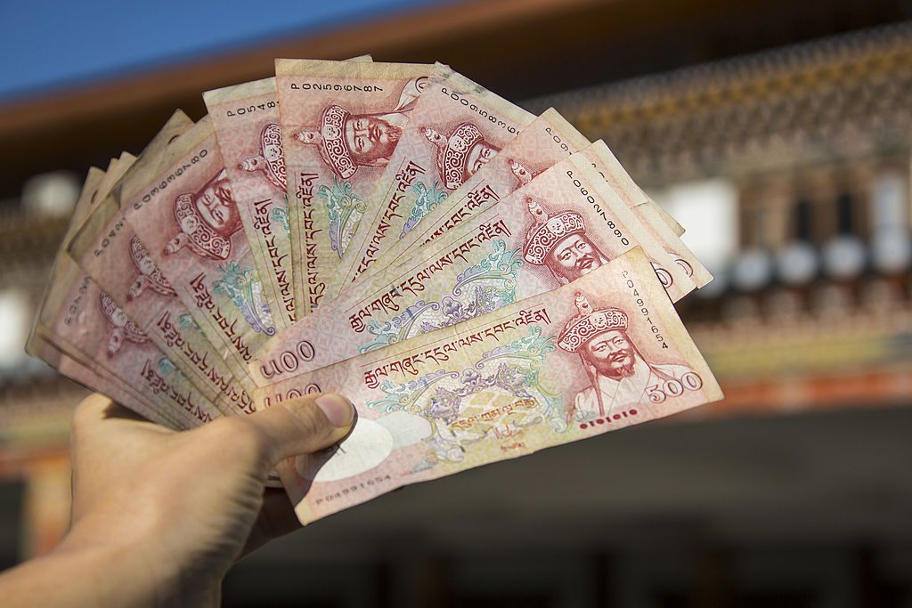 Paro, BHUTAN - NOVEMBER 18: Tourist showing notes of the Bhutanese currency Ngultrum after immigration, passport control after arrival with the Royal Bhutan Airline Drukair at Paro Airport , one of the most dangerous airports in the world on November 18, 2012 in Paro near Thimphu, Bhutan. (Photo by EyesWideOpen/Getty Images)