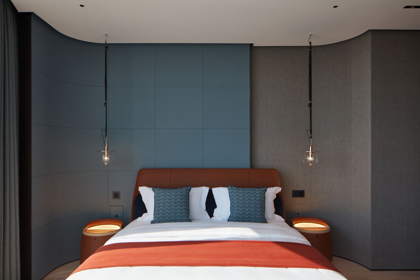 One of the bedrooms in the apartment, which features a stitched leather wall in a soothing teal shade