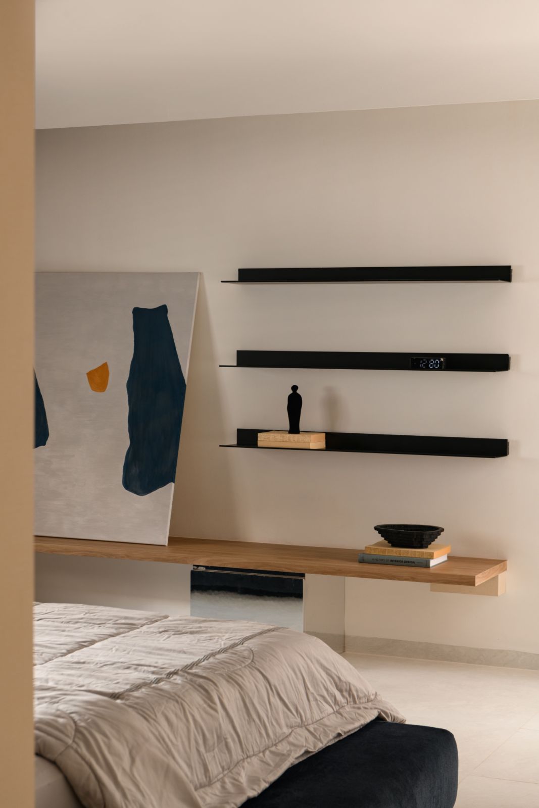 Minimalist floating shelves offer both practical storage and architectural interest while maintaining the bedroom’s serene atmosphere