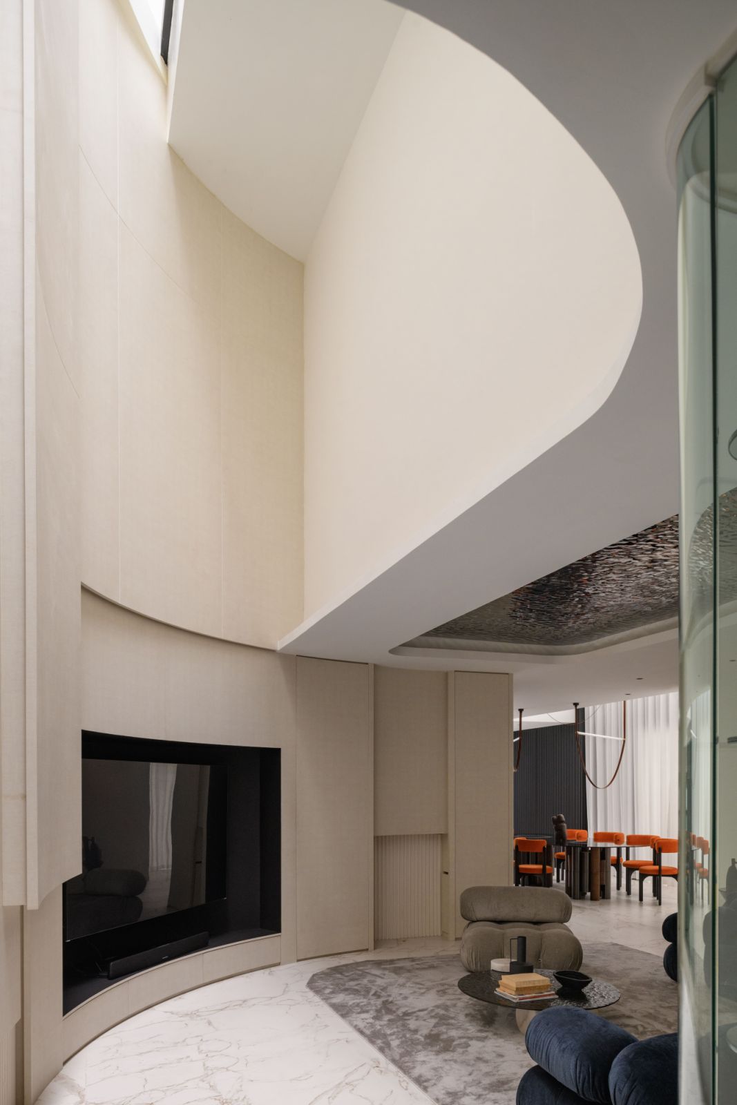 A curved ceiling sweeps elegantly above the living area, while water-ripple stainless-steel panels create an artistic contrast with plush furnishings